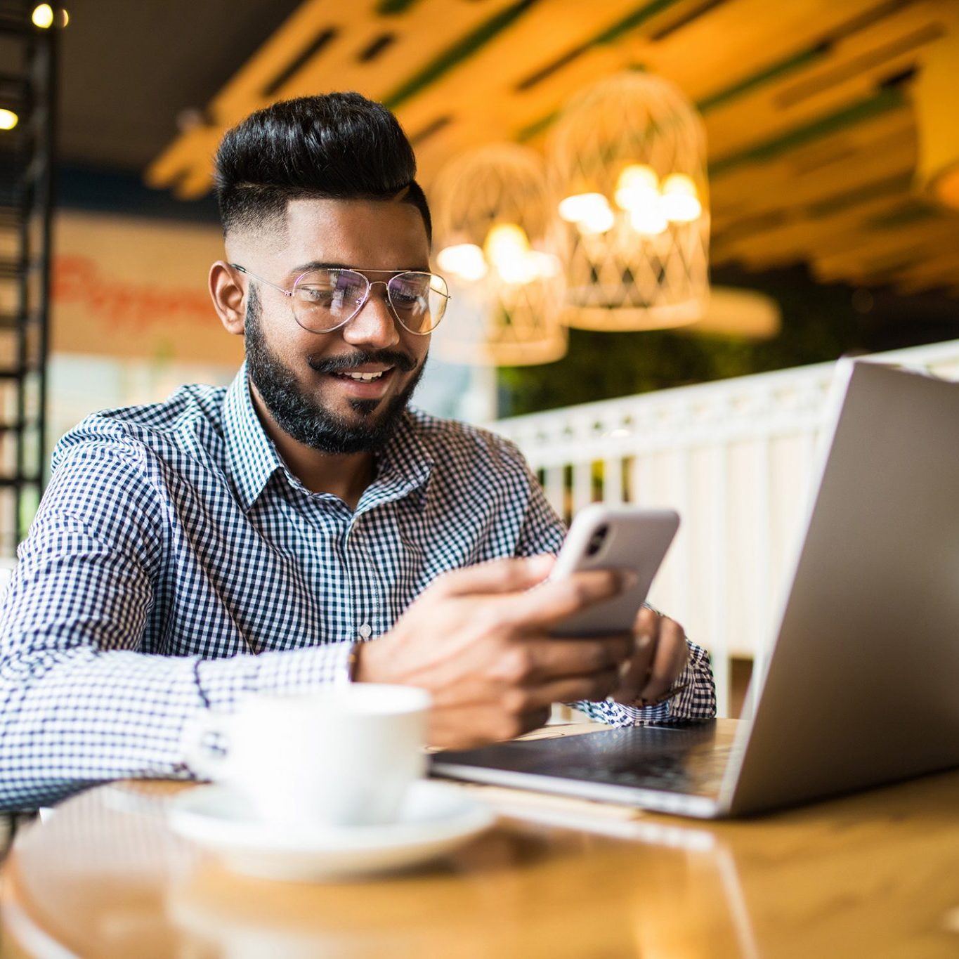 Portrait of indian man using laptop computer at workplace.